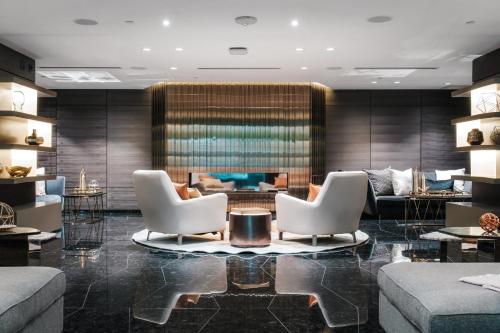 a lobby with two white chairs and a fireplace at Paradox Vancouver in Vancouver