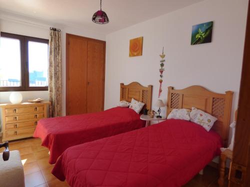 um quarto com 2 camas e lençóis vermelhos em Europlaya Atico em Calpe