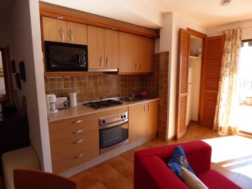 uma cozinha com armários de madeira e um sofá vermelho em Europlaya Atico em Calpe