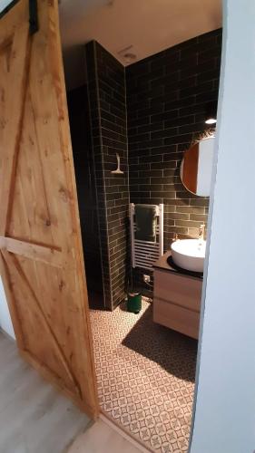 een badkamer met een houten deur en een wastafel bij Gastenverblijf Nummer 1 Sommelsdijk in Sommelsdijk