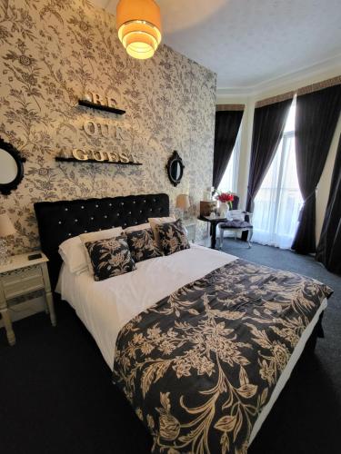 a bedroom with a bed with a black and gold bedspread at The Collingwood Guest House in Great Yarmouth