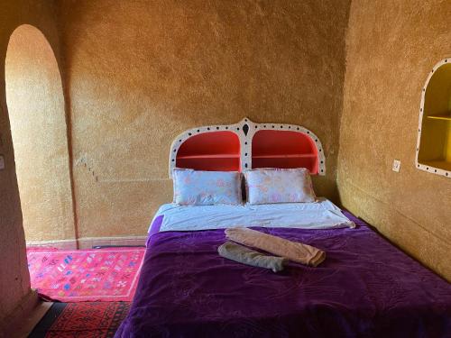 a bed with a red headboard in a room at Dar Yaya in Mhamid