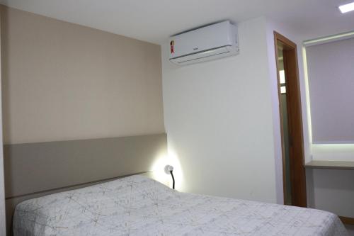 a bedroom with a bed and a light on the wall at Village Itacimirim, Pé na areia, Excelente 7B in Itacimirim