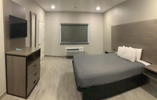 a bedroom with a bed and a flat screen tv at Americas Best Value Inn & Suites San Benito in San Benito