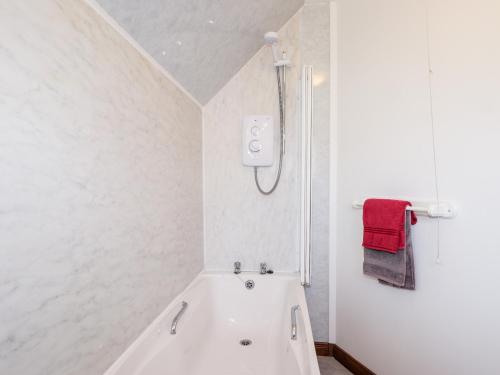 un bagno bianco con vasca e asciugamano rosso di Greshornish Boathouse a Edinbain