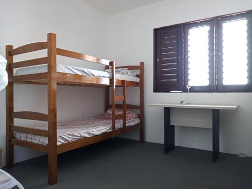 a room with bunk beds and a desk and a window at Casa Aconchegante Estilo Rústico na Praia in Barra de São Miguel