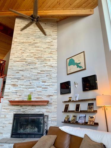 a living room with a brick fireplace with a ceiling fan at Stunning 3,400 sq ft Lake House w Boat Dock, Sauna, Steam Shower, and More in Clearlake Oaks