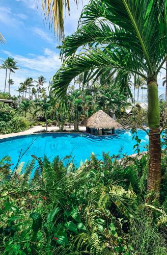 a resort with a blue swimming pool with a palm tree at Saletoga Sands Resort & Spa in Matatufu