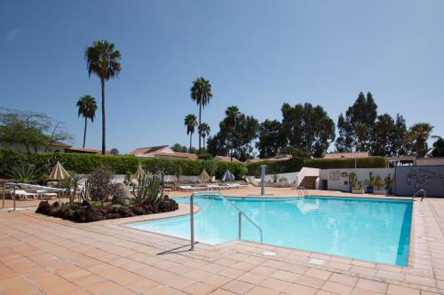 a swimming pool at a resort with palm trees at Serenity Garden in Maspalomas