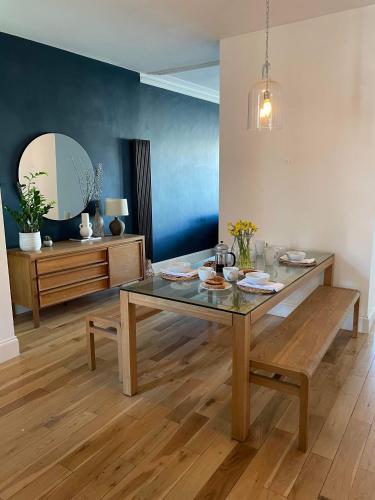 a dining room with a glass table and a bench at The Clock Tower Apartment - Spacious, Modern, 2 Bedroom Apartment , Southsea with Free parking - sleeps 4 in Portsmouth