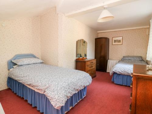 a bedroom with two beds and a dresser and a mirror at Carr Cottage in Boynton