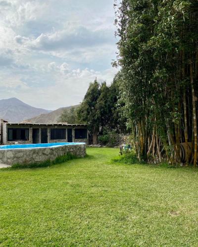 a house with a stone wall and a grass yard at Las Cabañas de Incahuasi in Lunahuaná