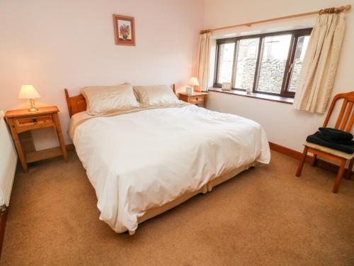 - une chambre avec un grand lit blanc et une fenêtre dans l'établissement Old Byre Cottage, à Ravenstonedale