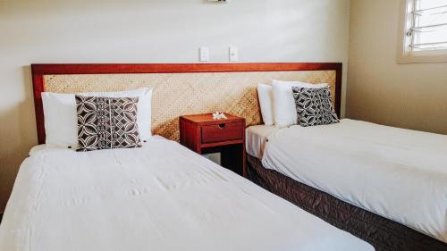 a bedroom with two beds and a night stand with a table at Saletoga Sands Resort & Spa in Matatufu