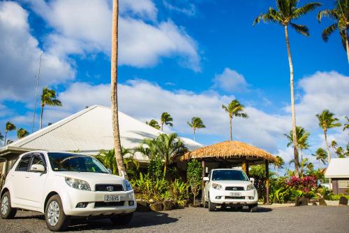 two white cars parked next to a building with palm trees at Saletoga Sands Resort & Spa in Matatufu