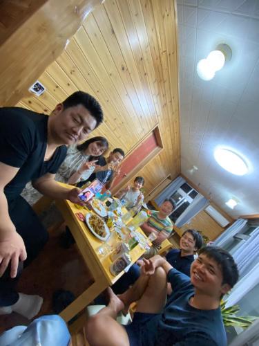 Un gruppo di persone seduti intorno a un tavolo che mangiano cibo di ゲストハウス喜舎場 a Isola di Ishigaki