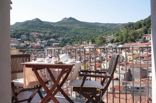 einen Tisch und Stühle auf einem Balkon mit Stadtblick in der Unterkunft Il Lupo Rosso in Santu Lussurgiu