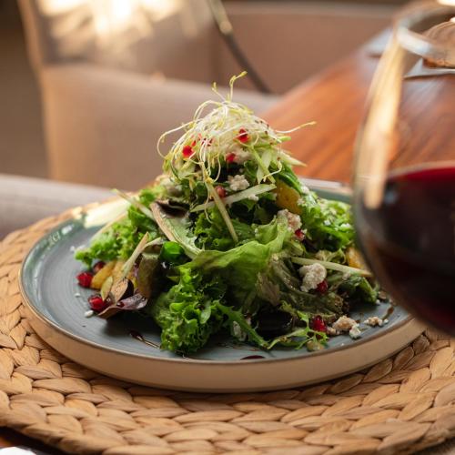 a plate of salad on a table with a glass of wine at RAW BEACH HOTEL in Antalya