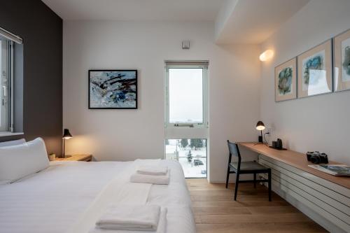 a bedroom with a bed and a desk and a window at Kaku Place by H2 Life in Furano