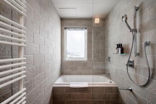 a bathroom with a bath tub and a shower at Kaku Place by H2 Life in Furano