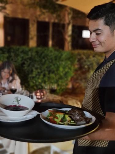 a man holding a table with a plate of food at Hacienda Historica Marchigue in Marchihue