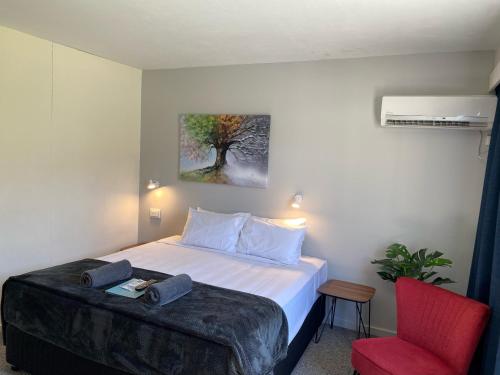a bedroom with a bed and a red chair at Mid City Motor Inn in Mackay