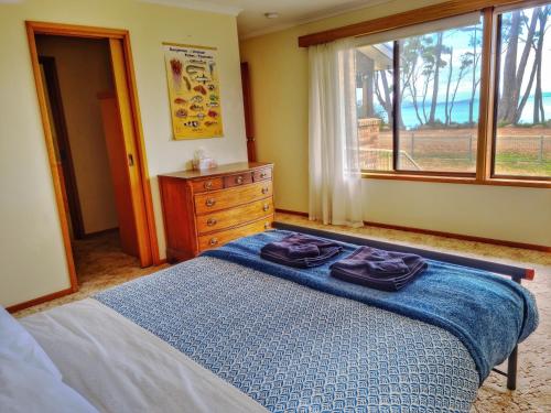 a bedroom with a bed and a dresser and a window at Sea Eagle at Roaring Beach in Surveyors Bay