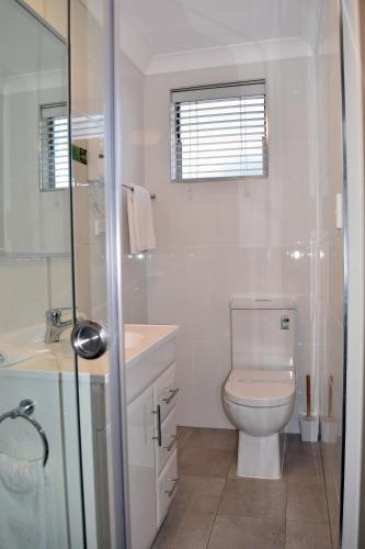 a white bathroom with a toilet and a shower at Ten Dollar Town Motel in Gulgong