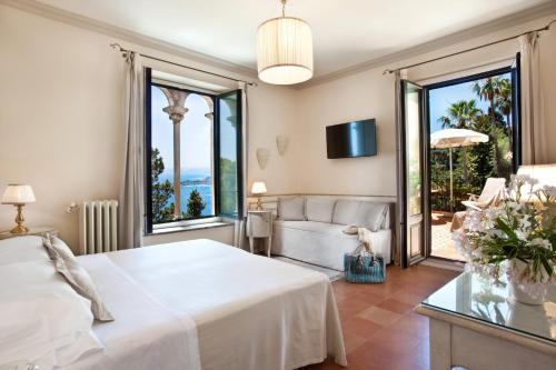 a bedroom with a bed and a couch and windows at Hotel Villa Belvedere in Taormina