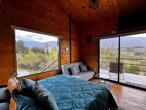 ein Schlafzimmer mit einem Bett und einem großen Fenster in der Unterkunft Villa Skape - Finca Villa Carolina in Villa de Leyva