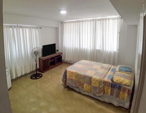 1 dormitorio con 1 cama, TV y cortinas en Habitaciones privadas en un departamento encantador, en Panamá