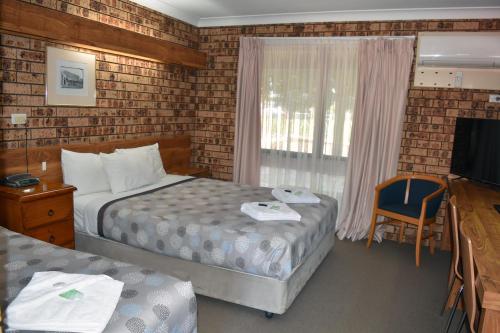 a hotel room with two beds and a television at Ten Dollar Town Motel in Gulgong
