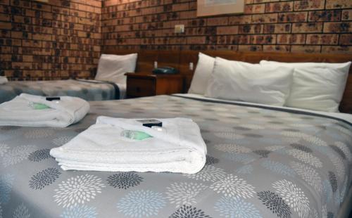 two towels on a bed in a hotel room at Ten Dollar Town Motel in Gulgong