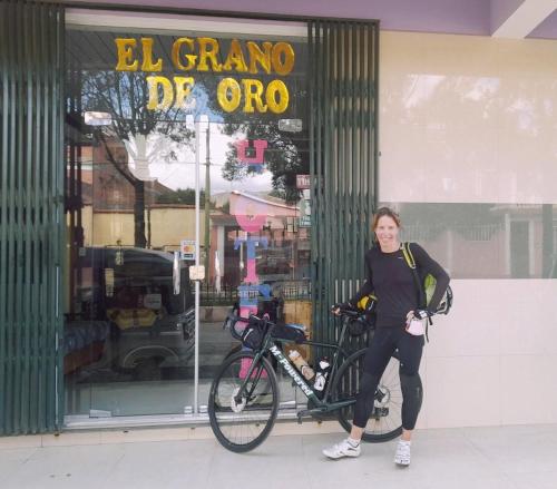 uma mulher ao lado de uma bicicleta em frente a uma loja em El Grano De Oro Hotel em Tupiza