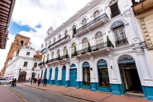 um edifício branco com acabamento azul numa rua em Del Parque Hotel & Suites em Cuenca