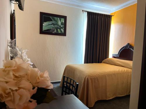 a hotel room with two beds and a table with flowers at Hotel Delicias Tequila in Tequila
