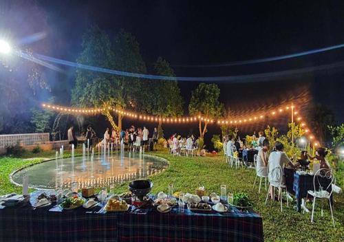 a group of people sitting around a table in the grass at Gia Trinh Farmstay Ba Vi - Venuestay in Hanoi