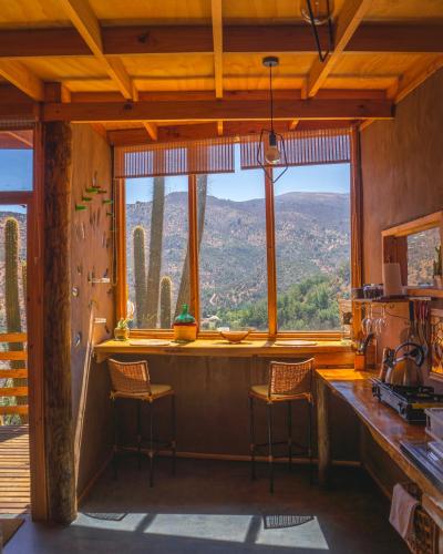 a kitchen with a large window and a counter with stools at Origen del Maipo Lodge in San José de Maipo