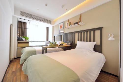 1 dormitorio con 2 camas y escritorio en 银座精宿济南长清大学城店, en Changqing