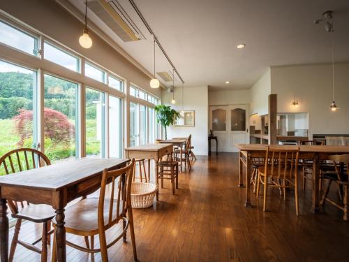 a dining room with tables and chairs and windows at café&GuestHouse kaziya in Ichinoseki