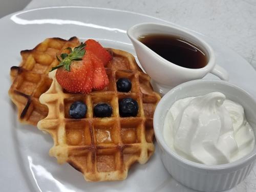 a plate of waffles with berries and a cup of coffee at Ten Dollar Town Motel in Gulgong