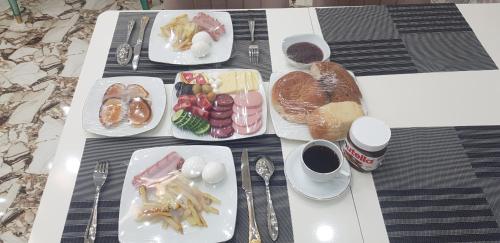 a table with plates of breakfast food on it at Hotel Sharq in Dushanbe