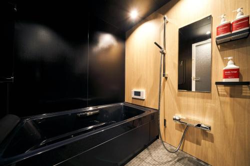 a bathroom with a black tub and a mirror at Rakuten STAY x EAGLES 101 with terrace in Sendai