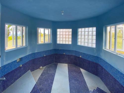 a bathroom with blue walls and windows and a tile floor at 'PARLATUVIER' 4 bedroom ocean view home in Saint Philip
