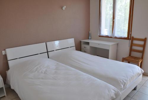 a bedroom with a white bed and a chair at Hôtel La Casera in Clarac