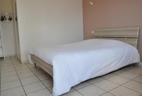 a bed in a bedroom with a white bedspread at Hôtel La Casera in Clarac