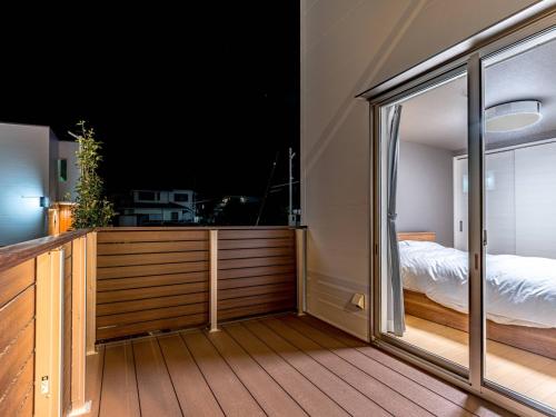 Rakuten STAY HOUSE x WILL STYLE Takasaki 101 في تاكاساكي: غرفة مع شرفة مع سرير ونافذة
