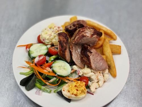 a white plate of food with meat and french fries at Ten Dollar Town Motel in Gulgong