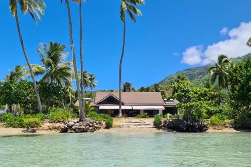 a house on a beach with palm trees and water at Villa Tiarenui in Maharepa