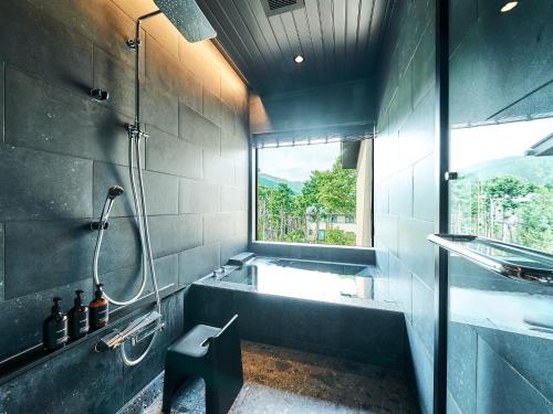 a bathroom with a tub and a shower and a window at Rakuten STAY VILLA Hakone Sengokuhara South Wing 101 BBQ Terrace capacity of 10 persons in Hakone